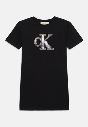 Čierne bavlnené tričko s krátkymi rukávmi a okrúhlym výstrihom, ktoré má na prednej strane veľké, metalické strieborné a modré logo "CK".