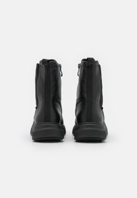 Botas negros tipo tobillo con cuero suave, paneles laterales elásticos y cierre de cremallera en la parte trasera. Suela de goma resistente para tracción.