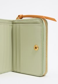 Interno di un portafoglio in pelle verde con scomparti per carte, dettagli in hardware dorato e una zip arancione. Texture liscia e bordi cuciti.
