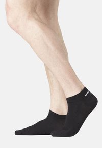 Chaussettes noires pour la cheville avec une texture douce, dotées d'un bourrelet côtelé et d'un petit logo blanc sur le côté. Convient pour un usage décontracté.