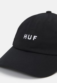 Czarna czapka bejsbolowa wykonana z teksturowanej tkaniny, z wygiękiem z przodu, z białym haftowanym logo "HUF" z przodu.
