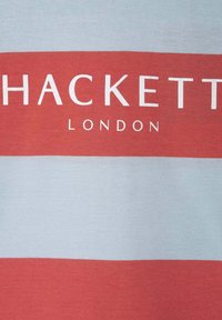 Červené a světle modré pruhované bavlněné tričko s bílým nápisem "HACKETT" a "LONDON", hladkou texturou a standardním střihem.