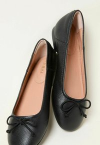 Schwarze Ballerinas aus strukturiertem Leder mit einem glatten Innenraum. Mit runder Zehenform und dekorativer Schleife an der Vorderseite. Niedriger Absatz.