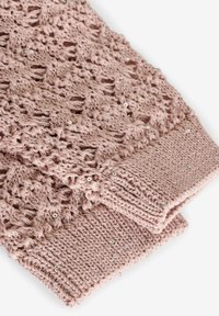 Veste tricotată de culoare roz pal, cu un design cu lucru deschis, împodobită cu mici paiete și cu manșete cu reumatism. Textură moale cu un model delicat.