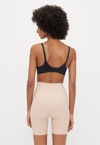 Must mustrakk mustrakk, reguleeritavad rihmad ja konksu sulgur. Nahatoonilised kõrge vöökoha lühikesed püksid ulatuvad keskmise reieni. Sile tekstuur.