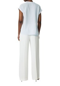 Lichtblauw gestreept shirt met korte mouwen en een ronde halslijn, gecombineerd met lange witte wijde broek. De stof lijkt zacht en glad te zijn.