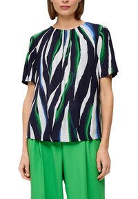 Blouse à manches courtes en tissu marine présentant des motifs ondulés abstraits verts et blancs. Texture lisse avec une coupe décontractée et un col plissé.