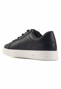 Black leather sneaker with white rubber sole, flat laces, and stitched detailing. Rounded toe and padded collar for comfort.