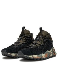 Chaussures de randonnée noires et vert olive avec une tige en daim texturé, une semelle à motif camouflage et des lacets réfléchissants avec une languette à l'arrière.