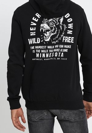 Czarna bluza z kapturem z graficznym wzorem przedstawiającym wilka oraz tekst. Wykonana z miękkiego materiału, ma kieszeń typu kangur i ściągacze przy mankietach.