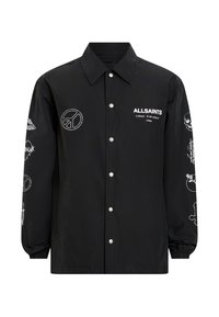 Giacca coach in nylon nera con ricami e loghi bianchi, caratterizzata da chiusura a scatto, colletto aperto e polsini elastici.