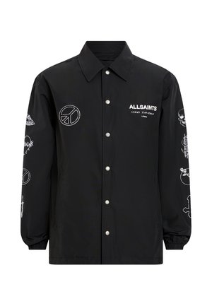 Veste coach en nylon noir avec broderie graphique et logos blancs, dotée d'une fermeture pression, d'un col évasé et de poignets élastiqués.