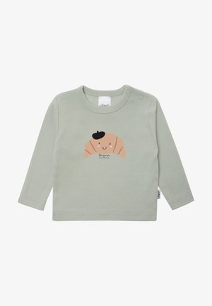 Langärmliges, mintgrünes Hemd aus weichem Baumwollstoff. Mit einem Croissant-Graphic mit einem lächelnden Gesicht und schwarzem Barett sowie einem Etikett am Kragen.