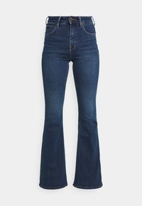 Höga utsvängda jeans i mörkblå denim. Har en smal passform genom låren, som vidgar sig nedanför knäna, med fem fickor.