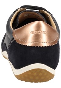 Chaussure en cuir noir et daim bleu marine avec un accent brillant en or rose au talon, dotée d'une semelle blanche à motif texturé.