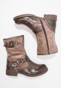 Bruna läderankelboots med en sidodragkedja, spännband, strukturerad finish och en låg klack. Designad för vardagsbruk.