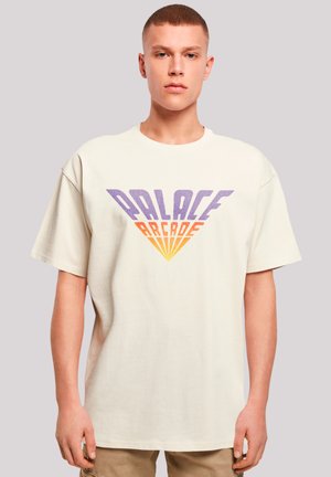 Cream cotton t-shirt featuring a large retro-style graphic in purple, orange, and yellow saying "PALACE ARCADE," with a boxy fit.