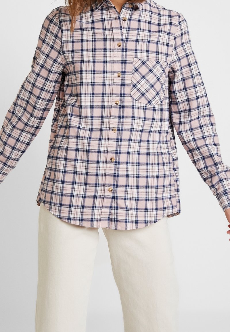 Rutig flanellskjorta i ljusrosa, marinblå och vit med långa ärmar, knappframsida och en enkel bröstficka med rutigt mönster.
