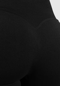 Hoge zwarte leggings met een soepele, rekbare textuur. Naadloos ontwerp met contourdetails voor een verbeterde pasvorm en vorm.