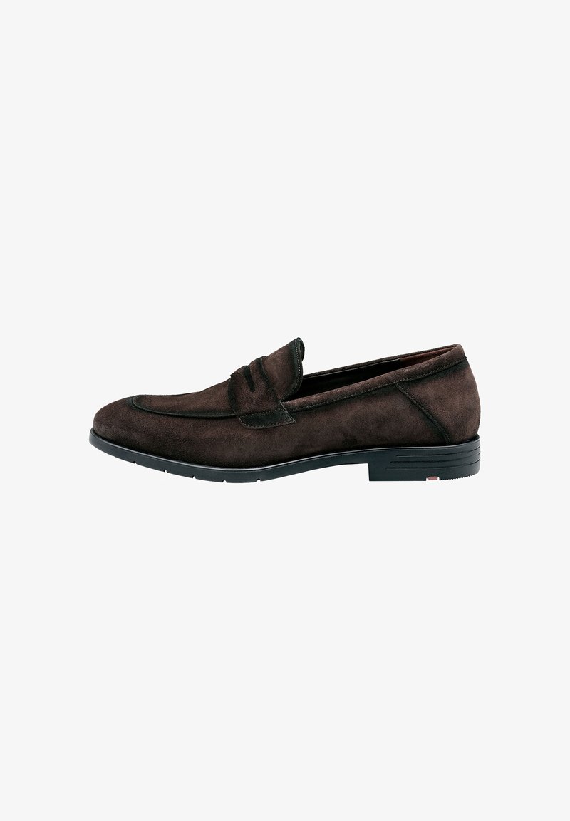 Mocassin en suède brun avec un bout arrondi, des coutures décoratives et une semelle en caoutchouc plate. À empeigne courte et texture lisse avec des accents minimalistes.