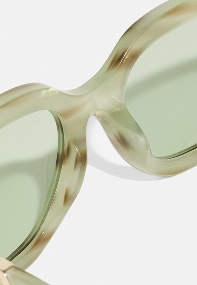 Óculos de sol com lente verde, apresentando uma armação translúcida de tom verde claro, com um design curvado único e textura suave.