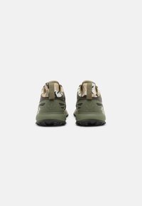 Baskets de sport camouflage vert et beige avec des matériaux texturés, un design bicolore et des semelles en caoutchouc noir ; comprend des languettes arrière.