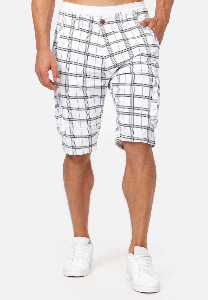 Shorts cargo à carreaux blancs avec des lignes vertes foncées, dotés de poches latérales et d'une fermeture à bouton. Fabriqués en tissu léger pour le confort.