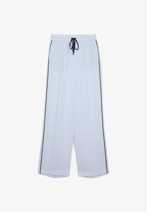 Lightweight white pants in a loose fit with black side stripes. Elastic waistband with a drawstring for adjustable comfort. Smooth texture.