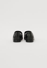 Pantofi negri din piele cu un finisaj neted, talpi plate și un design cu vârf rotunjit. Au un toc subtil și nu au hardware vizibil.