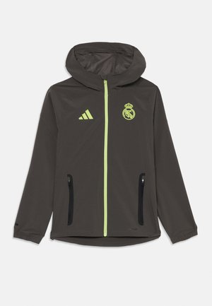 Veste légère grise avec capuche, dotée d'une fermeture éclair jaune-vert, d'un logo et d'accents. Deux poches zippées noires à l'avant.
