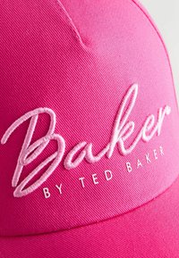 Casquette rose vif avec "Baker" brodé en cursive et "BY TED BAKER" imprimé en dessous sur le panneau avant.