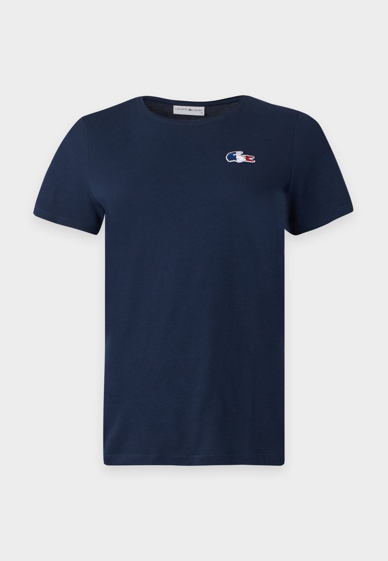 T-shirt bleu marine à manches courtes avec col rond et petit logo Lacoste rouge, blanc et bleu sur la poitrine gauche.