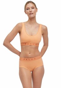 Oranje stretchstof beha en hoogsluitende slipset met FALKE-branding op de taillebanden. Gladde textuur, scoopnek ontwerp.