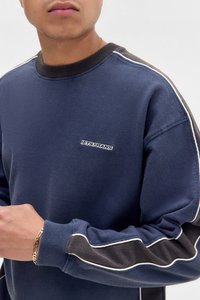 Mørkeblå sweatshirt med sorte detaljer og hvit piping. Har ribbet krage og broderte "LET'S FRANS"-logo på brystet.