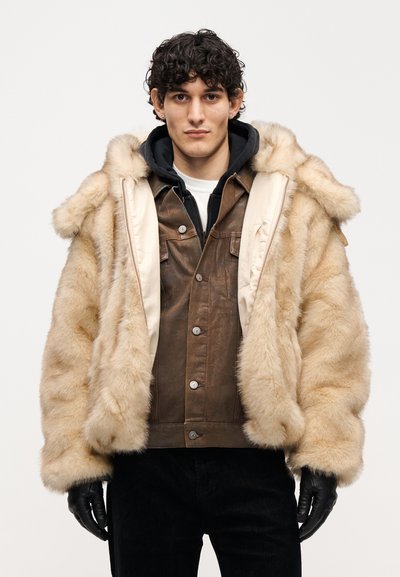 Μπουφάν από ψεύτικη γούνα με μπεζ εξωτερικό και καφέ δερμάτινη εσωτερική στρώση, με κουκούλα, κλείσιμο με φερμουάρ και μαύρα γάντια.
