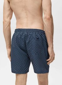 Șorturi de baie bleumarin cu un pattern geometric alb, talie elastică și două buzunare laterale, fiind realizate dintr-un material ușor și cu uscare rapidă.