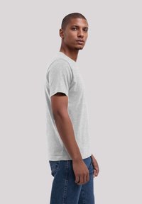 Grijze T-shirt met korte mouwen en een klassieke ronde hals, gemaakt van lichtgewicht katoen en in een relaxte pasvorm, gecombineerd met blauwe denim jeans.