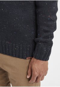 Mørkeblå strikket sweater med multicolore sprøjt, ribbede manchetter og kant, med et lille mærke nær taljen.