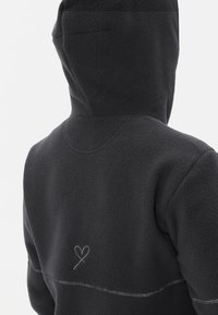 Felpa nera in pile con finitura testurizzata, dotata di cappuccio e ricamo a forma di cuore discreto sulla schiena, accentuato da cuciture a contrasto.