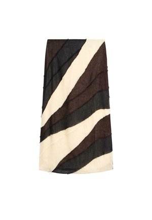 Personne marchant avec un haut noir à manches longues, une jupe longue rayée noire, blanche et marron, et des sandales noires à talons sur un sol lisse.