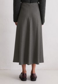 Grå, mid-length skjørt med en glatt tekstur, med baklukk og en utsvingt design. Kombinert med mørke, blanke sko.