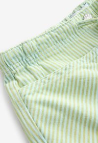 Groene en gele gestreepte stof met een elastische tailleband en een voorkantzak. De textuur is glad met een lichte glans.
