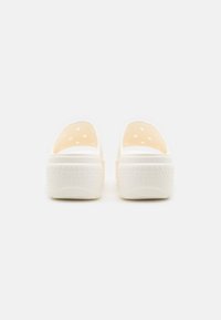 Bijele otvorene klompe napravljene od laganog materijala s ventilacijskim rupama, teksturiranom gumenom petom i "crocs" oznakom na petu.