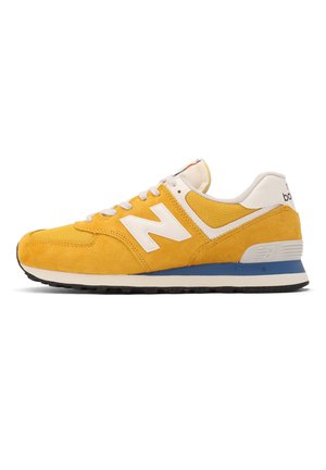 Baskets New Balance jaunes avec lacets blancs, logo blanc, semelle bleue et blanche, et semelle extérieure noire, vues de côté extérieur.