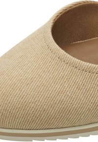 Scarpa beige slip-on con tomaia in tessuto testurizzato, apertura rotonda e suola color beige chiaro. Presenta cuciture sottili lungo i bordi.