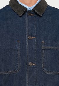 Dark blue denim jacket with a corduroy collar, featuring two front pockets, copper stitching, and brass button accents.