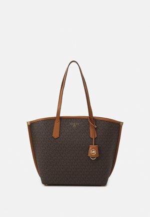 Sac cabas marron avec motif du logo Michael Kors, poignées en cuir fauve et badge pendentif avec emblème MK sur fond uni.
