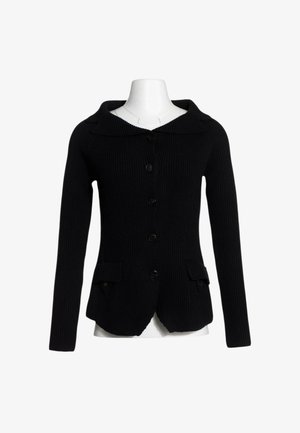 Cardigan nero lavorato a maglia con maniche lunghe, bottoni sul davanti, due tasche frontali con patta e una ampio colletto su un manichino bianco.