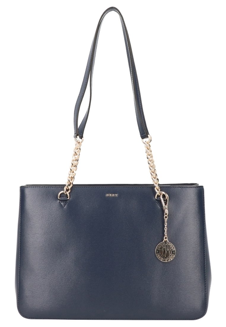 Sac à main en cuir bleu marine avec des anses en chaîne argentée et un pendentif décoratif, présentant une forme structurée et une texture lisse.