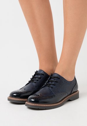 Chaussures brogue en cuir bleu marine avec une finition brillante, un design à lacets, des détails perforés et une semelle contrastante.